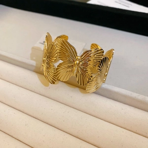 Detailed macro view of gold butterfly cuff bracelet with textured metallic wings