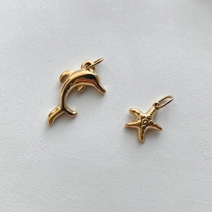 Macro shot of gold stainless steel dolphin and starfish pendants with textured finish