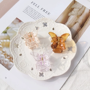 Detailed view of three mini resin butterfly hair clips in amber, pink and purple shades