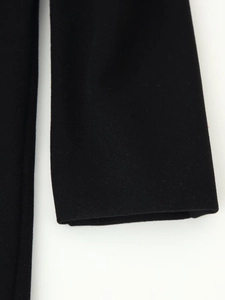 Close-up of black wool coat sleeve showing matte fabric texture and fine stitching detail