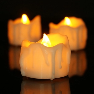 Detail of warm yellow LED tea lights with realistic melted wax effect on black surface