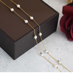 Detail of five round pearls and golden square accents on a titanium choker necklace