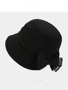 Detail of black bow sun hat featuring unique wavy pleated texture and elegant design