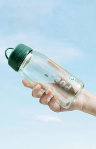 Détail d'une bouteille d'eau en plastique vert avec dragonne sur fond de ciel bleu