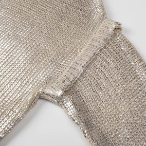 Detail of armhole seam and metallic knit texture on champagne gold sweater