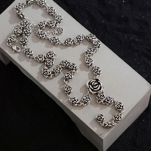 Vintage S925 silver rose necklace featuring detailed floral links on a gray stone