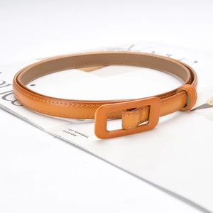 Orange-brown slim leather belt with wrapped buckle on a magazine for women's fashion