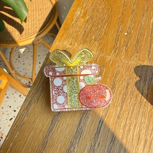 Cute pink gift box acrylic hair clip with white dots and red apple on a wooden table