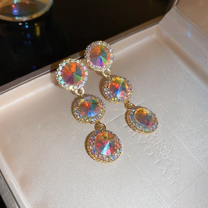 Macro view of triple-layered teardrop earrings with iridescent stones and gold finish
