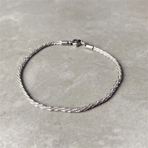 Detail eines silbernen Mesh-Armbands mit Karabinerverschluss auf steinigem Hintergrund