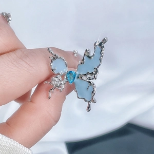 Detail of irregular butterfly ring with blue gemstone and liquid metal silver finish