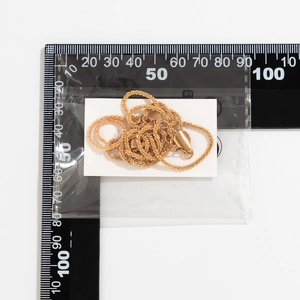 Detailed close-up of a minimalist golden layered chain necklace with a measurement ruler