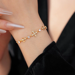 Gros plan du bracelet croix doré scintillant avec strass sur le poignet d'un modèle