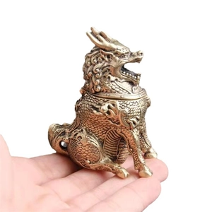 Miniature brass Kirin incense burner with intricate scales shown in hand for scale