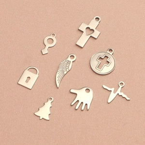 Gros plan de pendentifs en acier titane argenté en formes de croix, clé, serrure et ailes