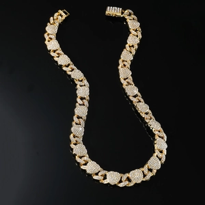 Collier maille cubaine dorée avec strass étincelants sur fond noir réfléchissant