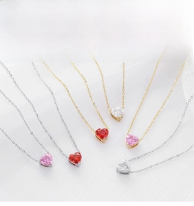 Detalle de collares de corazón con gemas rojas, rosas y blancas en cadenas doradas