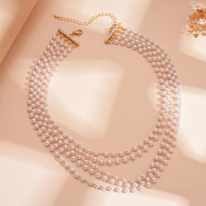 Close-up of four-layer faux pearl necklace with gold chain and rhinestone accents
