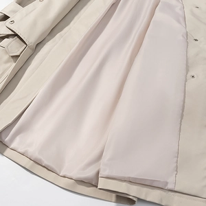 Detailed view of beige trench coat interior showing smooth lining and fine stitching