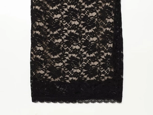 Close-up of black floral lace fabric with intricate cutouts and scalloped hemline detail