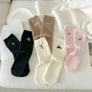 Flat lay of four plush thermal socks with cute animal embroidery in soft colors