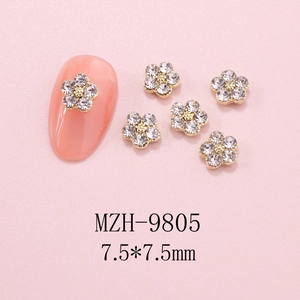Macro shot of 7.5mm gold base five-petal flower nail charms with crystal rhinestones