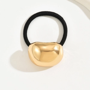Minimalist elastic hair tie with a large irregular golden bean metal ornament on white