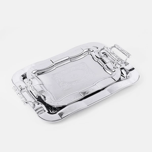 Detail of silver rectangular nested serving trays with ornate floral engravings and handles