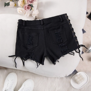 Dettaglio degli shorts in denim nero con lacci laterali e bordi sfrangiati strappati
