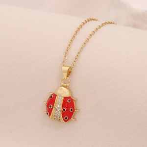 Dettaglio del ciondolo a coccinella dorata con smalto rosso e micro-pave di cristalli
