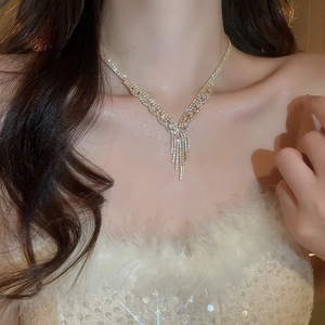 Close-up of golden V-shaped necklace with tassel rhinestones worn by a model