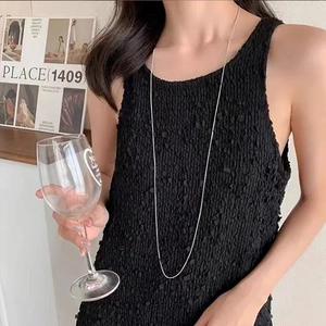 Detail of slim long silver titanium steel snake chain worn with a chic black outfit