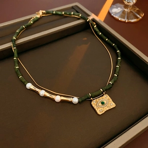 Dettaglio collana vintage con perline di bambù, perle e ciondolo occhio di Allah