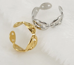 Primer plano de anillos de eslabones café en oro y plata sobre piel blanca suave