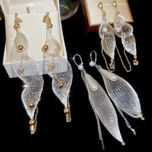 Detailed view of silver mesh drop earrings with pearls and tassels on a black background