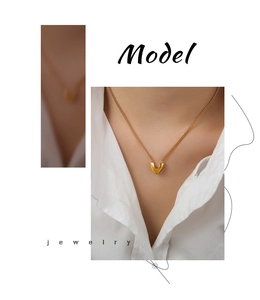 Collier élégant avec pendentif cœur doré porté par un mannequin en chemise blanche