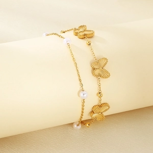 Detail of double-layer gold butterfly chain bracelet featuring white pearls on a stand