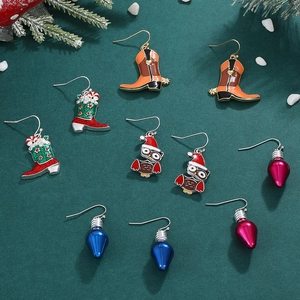 Christmas earring set with festive cowboy boots, owls and light bulb charms on green background