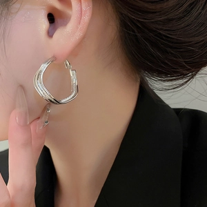Close-up of model wearing irregular silver textured hoop earring for a modern chic look