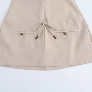 Dettaglio minigonna beige a trapezio stile preppy con coulisse e tasche con bottoni