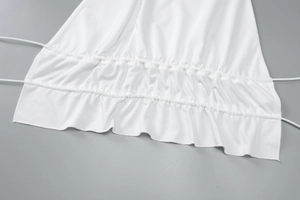 Detail view of white skirt hem featuring adjustable side drawstrings and ruched fabric