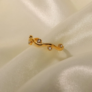 Close-up of 18K gold leaf-shaped ring with small diamonds on white silk fabric