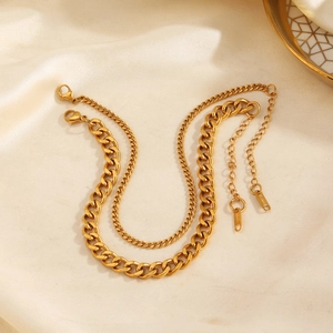 Golden stainless steel Cuban chain anklets displayed on elegant beige silk fabric