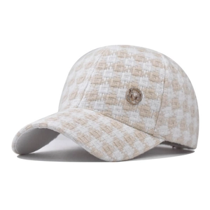 Detail of tweed houndstooth baseball cap featuring a gold M logo emblem with rhinestones