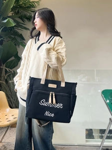 Close-up of black canvas tote bag with beige straps and Summer Nice embroidery detail