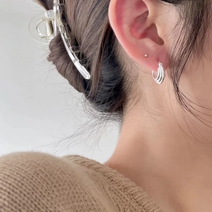 Detail of layered triple hoop sterling silver earrings shown on model for a chic look