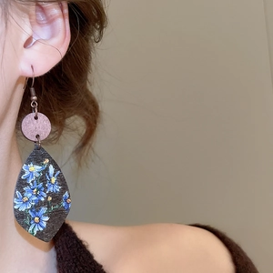 Detail view of Bohemian teardrop wooden earrings with blue daisy floral print and metal hook