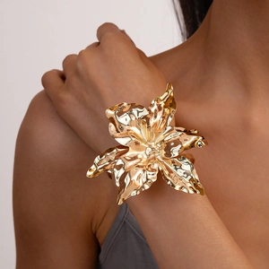 Macro shot of layered gold flower petal cuff showing detailed metallic folds and textures
