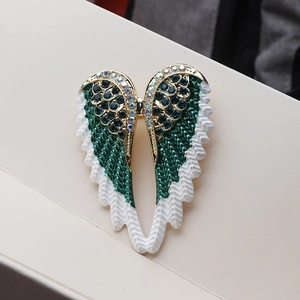 Detail of angel wing brooch with green enamel inlay and sparkling colorful rhinestones