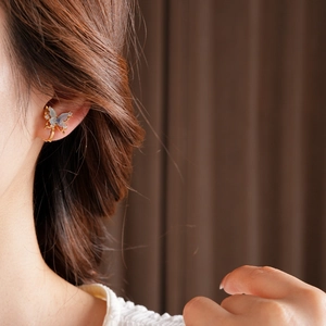 Detail of 18k gold plated butterfly ear cuff with blue crystals on model's ear